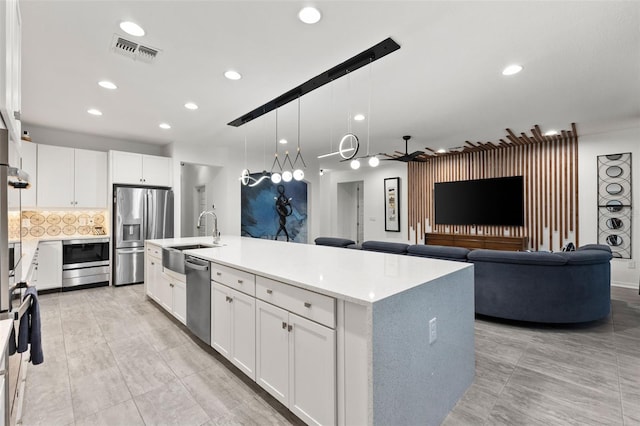 kitchen featuring ceiling fan, white cabinetry, stainless steel appliances, and an island with sink