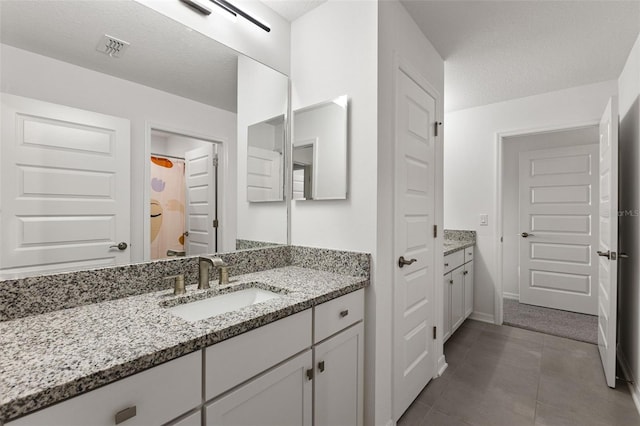 bathroom with a textured ceiling, tile patterned floors, and vanity