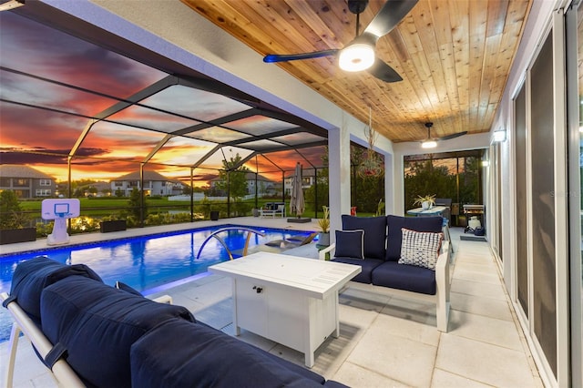 pool at dusk featuring ceiling fan, an outdoor living space, a patio area, and a lanai