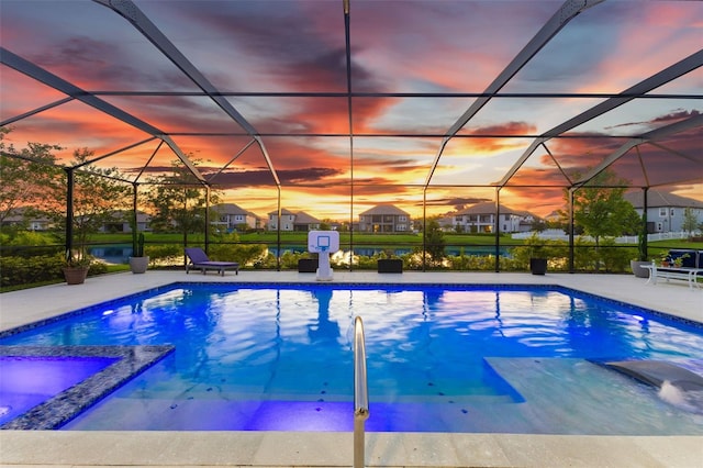 pool at dusk with glass enclosure and a patio area