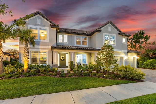 mediterranean / spanish home featuring a lawn and a garage