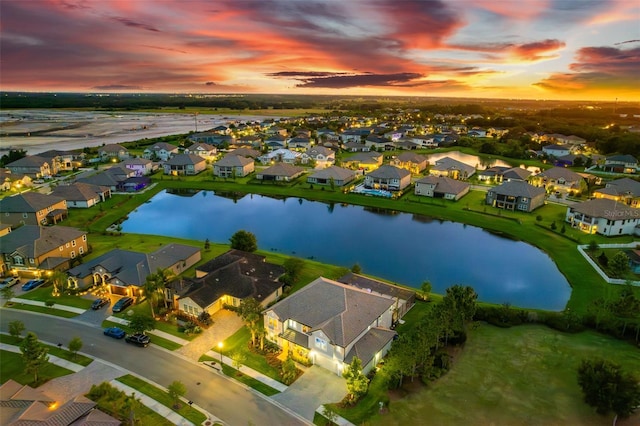 aerial view at dusk featuring a water view