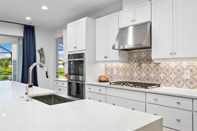 kitchen with backsplash, sink, light stone countertops, appliances with stainless steel finishes, and white cabinets