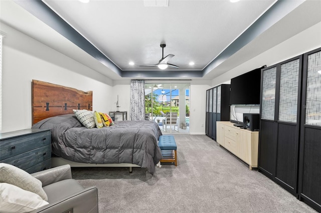 bedroom with light carpet, ceiling fan, access to outside, and a tray ceiling