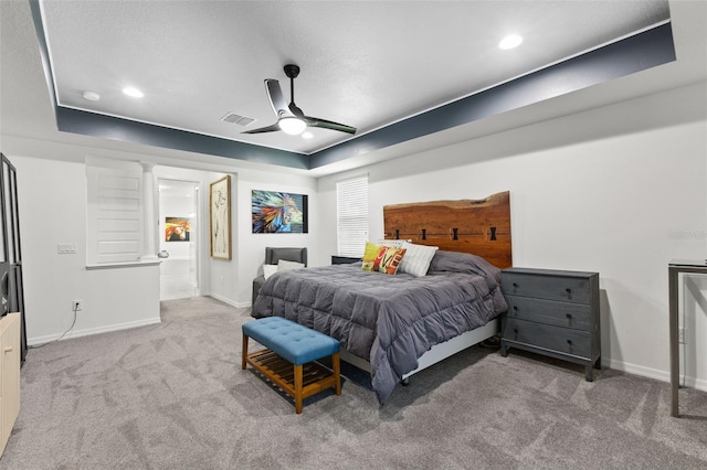 carpeted bedroom with ceiling fan and a raised ceiling