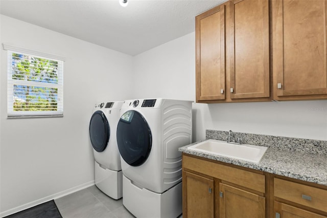 laundry room with washing machine and dryer, cabinets, light tile patterned flooring, and sink