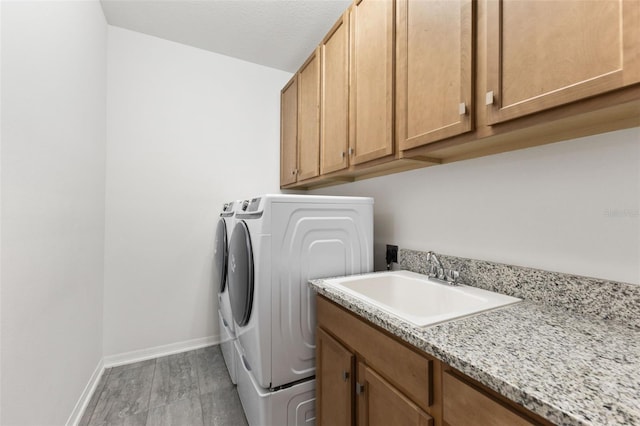 washroom with washing machine and dryer, cabinets, hardwood / wood-style floors, and sink