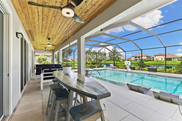 view of pool featuring a water view, glass enclosure, a patio area, and a hot tub