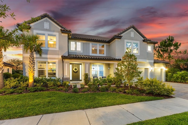 7135 Graybrook Dr, Wesley Chapel, FL 33545 - mediterranean / spanish home featuring a tiled roof, a yard, a garage, stucco siding, and driveway