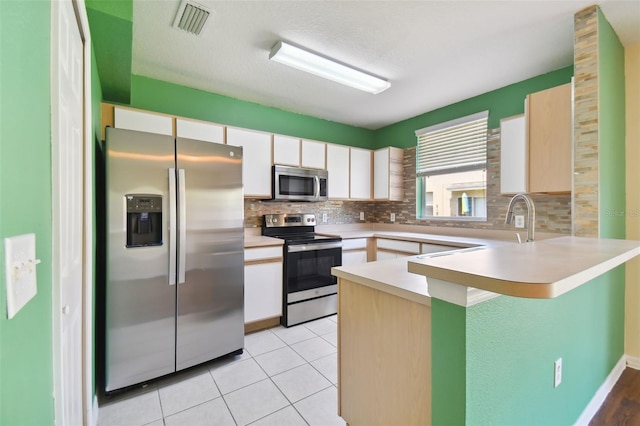 kitchen with white cabinetry, tasteful backsplash, kitchen peninsula, and stainless steel appliances