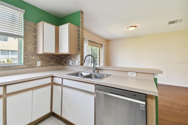 kitchen with white cabinetry, light hardwood / wood-style floors, stainless steel dishwasher, sink, and tasteful backsplash