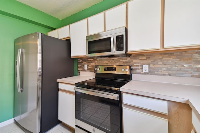 kitchen featuring backsplash, white cabinets, light tile floors, and appliances with stainless steel finishes