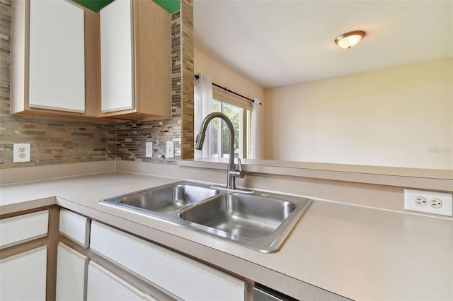 kitchen featuring backsplash, sink, and white cabinetry