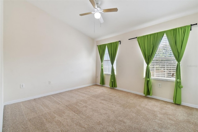 carpeted empty room featuring plenty of natural light, ceiling fan, and lofted ceiling