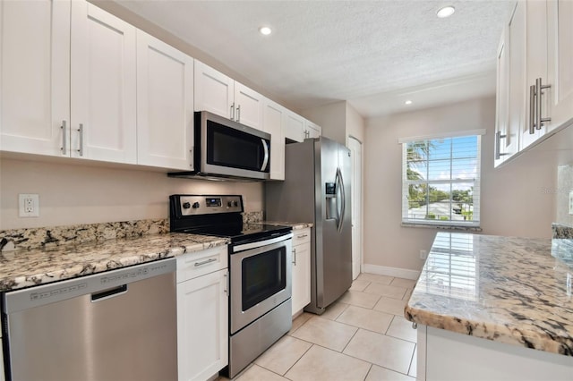 kitchen featuring white cabinetry, light tile patterned floors, light stone countertops, and appliances with stainless steel finishes