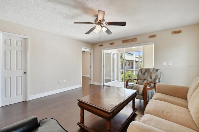 living room with ceiling fan, dark hardwood / wood-style floors, and a textured ceiling