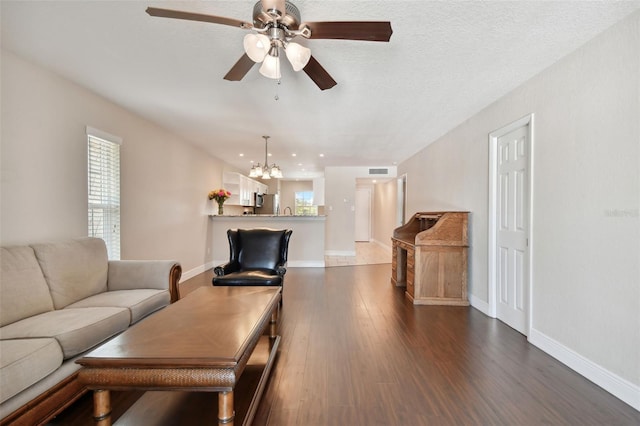 living room with ceiling fan with notable chandelier and dark hardwood / wood-style floors