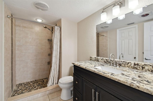 bathroom with vanity, a textured ceiling, tile patterned floors, toilet, and walk in shower