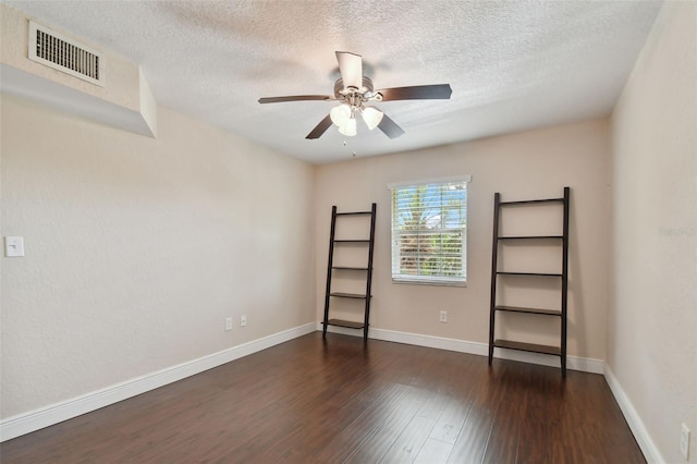 unfurnished room with a textured ceiling, dark wood-type flooring, and ceiling fan