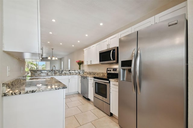 kitchen featuring appliances with stainless steel finishes, kitchen peninsula, pendant lighting, light stone countertops, and white cabinets