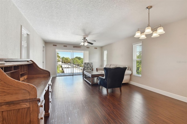 interior space with dark hardwood / wood-style floors, ceiling fan with notable chandelier, and a textured ceiling