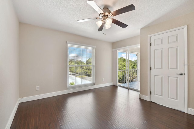 empty room featuring ceiling fan, dark wood-type flooring, and a textured ceiling