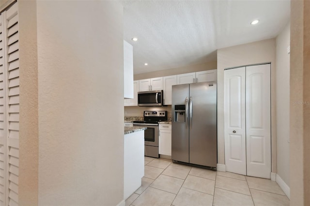 kitchen with white cabinetry, appliances with stainless steel finishes, light tile patterned flooring, and light stone counters