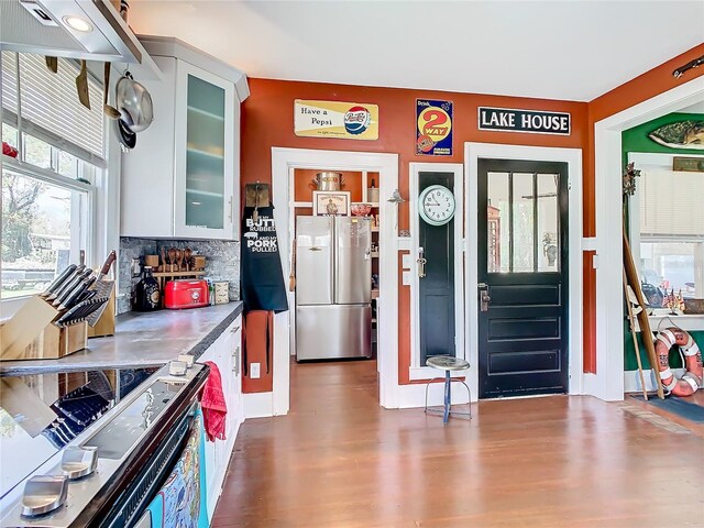 kitchen with backsplash, dark hardwood / wood-style floors, stainless steel fridge, electric range oven, and white cabinetry