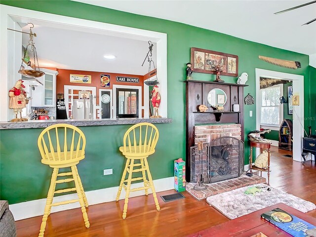 bar with a fireplace, hardwood / wood-style floors, and white refrigerator