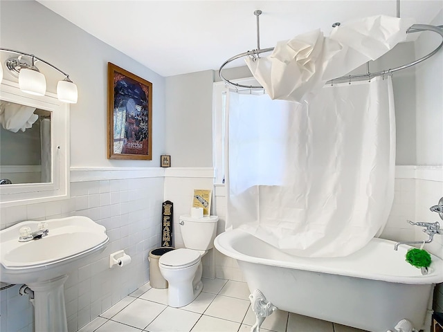 bathroom with tile patterned flooring, shower / bath combo, toilet, and tile walls