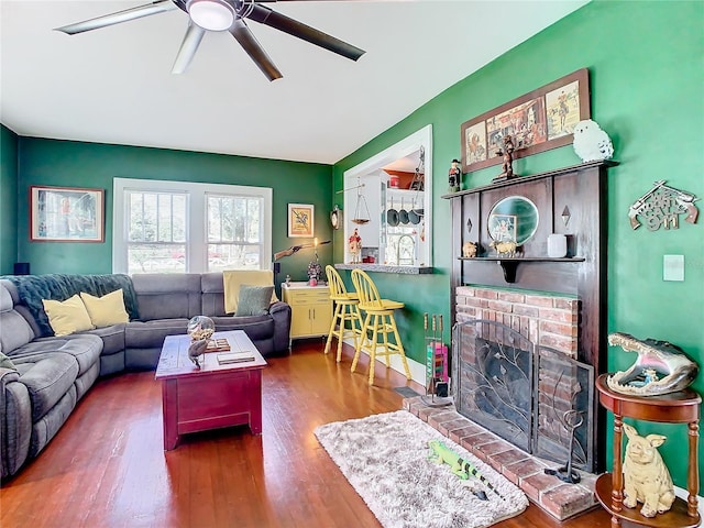 living room featuring hardwood / wood-style floors, ceiling fan, and a fireplace