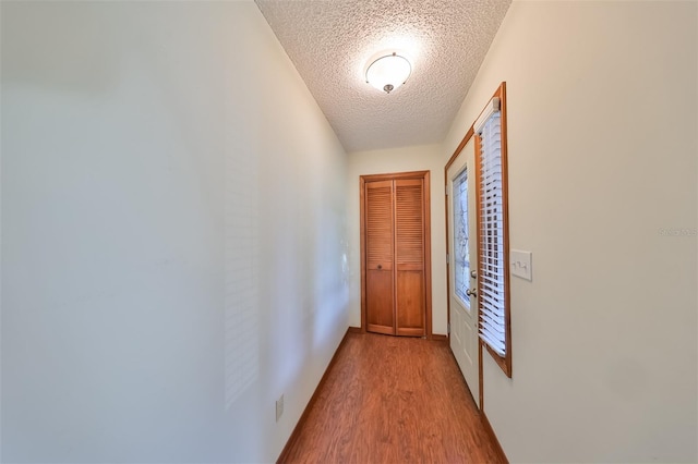 corridor featuring a textured ceiling and light hardwood / wood-style flooring