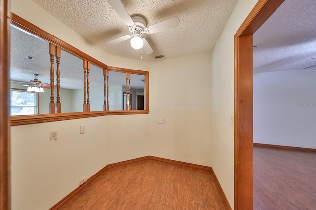 empty room featuring ceiling fan, a textured ceiling, and light wood-type flooring