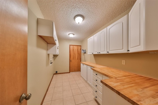 laundry area with cabinets, a textured ceiling, light tile patterned floors, and hookup for a washing machine