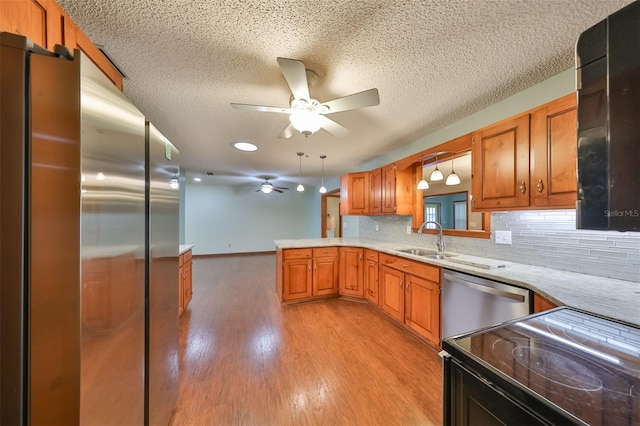 kitchen with decorative backsplash, sink, decorative light fixtures, kitchen peninsula, and stainless steel appliances