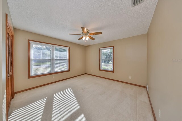 carpeted spare room featuring ceiling fan and a textured ceiling