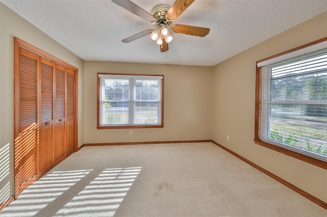 unfurnished bedroom with a closet, ceiling fan, a textured ceiling, and light carpet