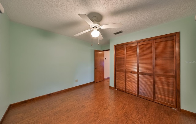 unfurnished bedroom featuring light wood-type flooring, a textured ceiling, a closet, and ceiling fan