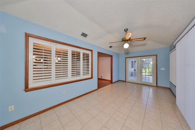 empty room featuring a textured ceiling, light tile patterned floors, ceiling fan, and french doors