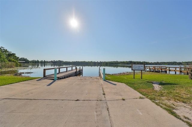 dock area with a lawn and a water view