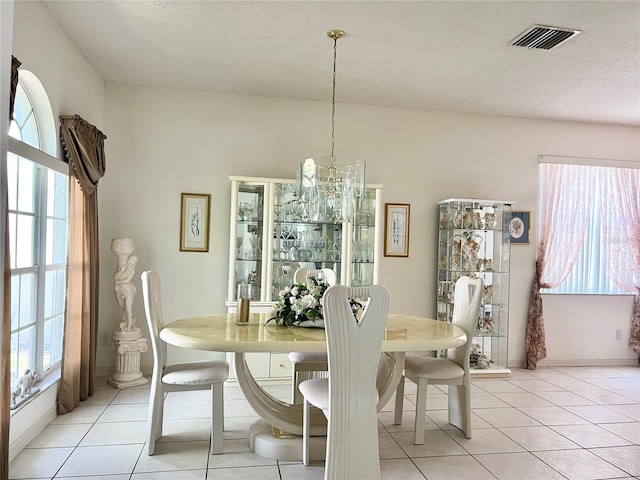 dining room featuring light tile patterned floors, a textured ceiling, and a notable chandelier