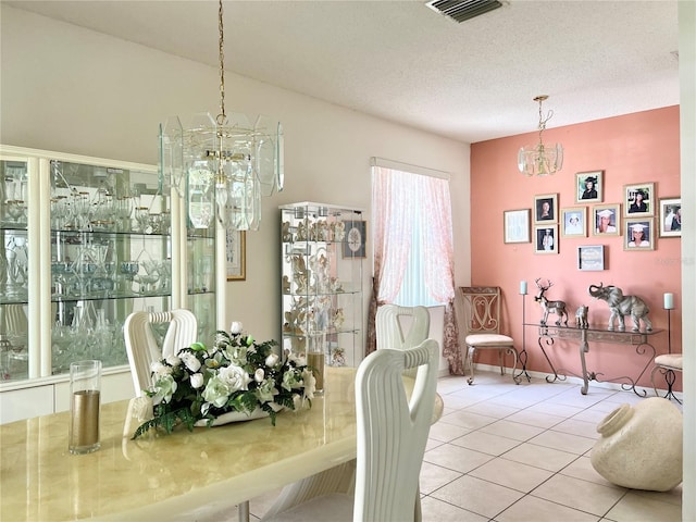 dining area with a chandelier, a textured ceiling, and tile patterned flooring