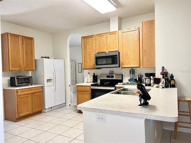 kitchen featuring a kitchen breakfast bar, kitchen peninsula, a textured ceiling, and appliances with stainless steel finishes