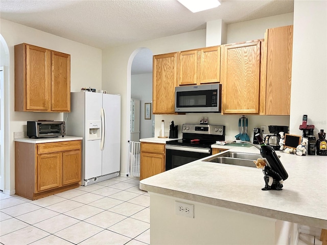 kitchen featuring light tile patterned floors, a textured ceiling, and stainless steel appliances