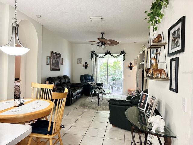 living room with ceiling fan, light tile patterned floors, and a textured ceiling