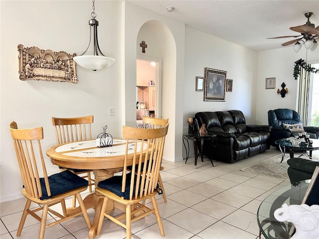 tiled dining space featuring a textured ceiling and ceiling fan