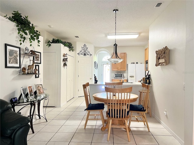 dining area featuring light tile patterned floors and a textured ceiling