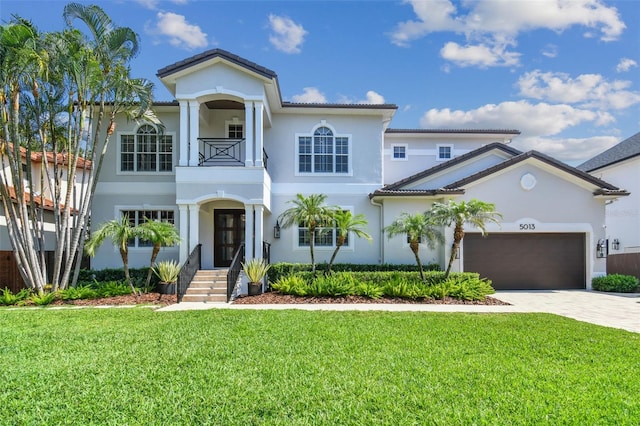 view of front facade featuring a garage, a balcony, and a front lawn