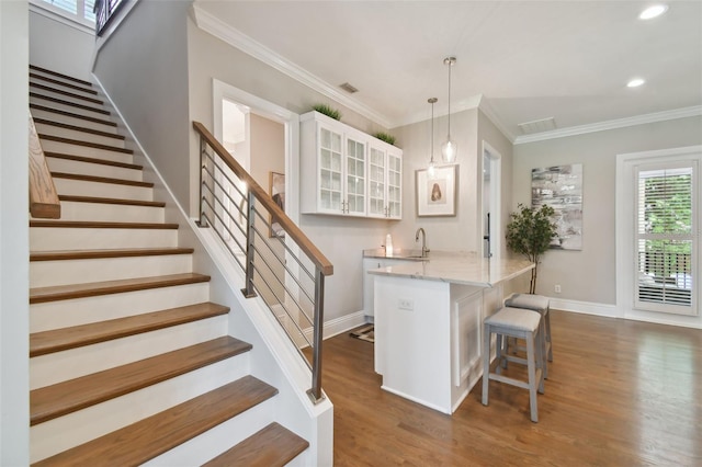 stairway featuring sink, crown molding, and wood-type flooring