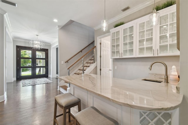 kitchen featuring light stone counters, dark hardwood / wood-style flooring, a breakfast bar, and pendant lighting